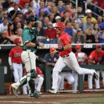 Arizona's Zach Gibbons (23) scores on a Bobby Dalbec single as Coastal Carolina catcher David Parrett looks on in the first inning in Game 2 of the NCAA Men's College World Series finals baseball game in Omaha, Neb., Tuesday, June 28, 2016. (AP Photo/Ted Kirk)