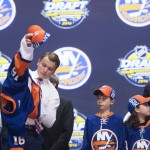 Kieffer Bellows puts on his sweater as he stands on stage with members of the New York Islanders management team at the NHL hockey draft, Friday, June 24, 2016, in Buffalo, N.Y. (Nathan Denette/The Canadian Press via AP)