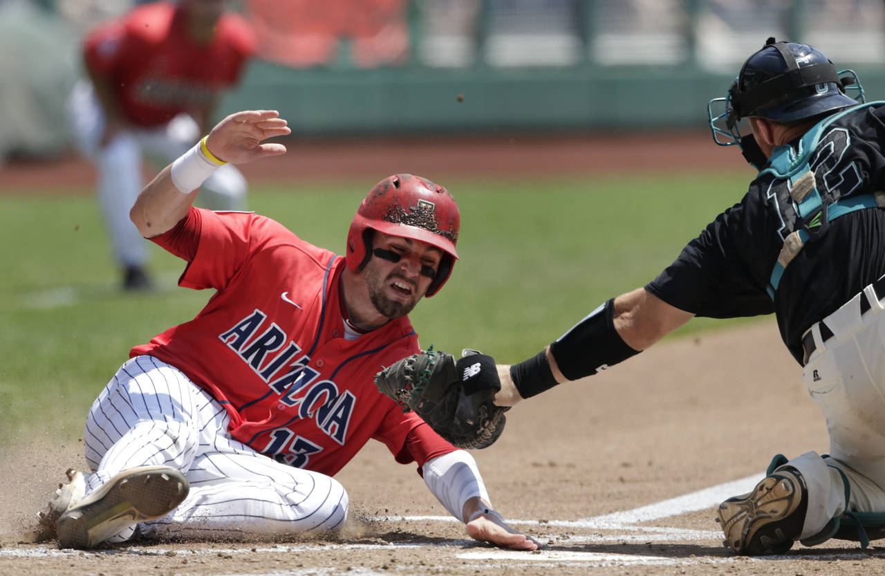 Arizona's Cody Ramer (13) is tagged out at home plate by Coastal Carolina catcher David Parrett (12) in the third inning in Game 3 of the NCAA College World Series baseball finals in Omaha, Neb., Thursday, June 30, 2016. (AP Photo/Nati Harnik)