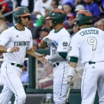 Miami's Brandon Lopez, left, is greeted by Edgar Michelangeli (16) and Carl Chester (9) after scoring against Arizona on a single by Christopher Barr in the fourth inning of an NCAA men's College World Series baseball game in Omaha, Neb., Saturday, June 18, 2016. (AP Photo/Nati Harnik)