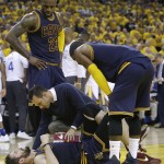 A trainer checks on Cleveland Cavaliers forward Kevin Love, bottom, as forward LeBron James (23) and guard Kyrie Irving watch during the first half of a Game 2 of basketball's NBA Finals against the Golden State Warriors in Oakland, Calif., Sunday, June 5, 2016. (AP Photo/Marcio Jose Sanchez)