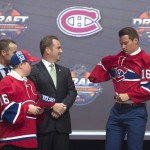 Mikhail Sergachev, ninth overall pick, puts on his sweater as he stands on stage with members of the Montreal Canadiens management team at the NHL hockey draft, Friday, June 24, 2016, in Buffalo, N.Y. (Nathan Denette/The Canadian Press via AP)