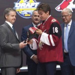 Clayton Keller, seventh overall pick, is given a hat as he stands on stage with members of the Arizona Coyotes management team at the NHL hockey draft, Friday, June 24, 2016, in Buffalo, N.Y. (Nathan Denette/The Canadian Press via AP)