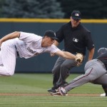 Colorado Rockies second baseman DJ LeMahieu, left, tries to tag out Arizona Diamondbacks' Jean Segura as he slides safely back into second base after rounding the base and stumbling on a single by Michael Bourn during the first inning of a baseball game Friday, June 24, 2016, in Denver. Second bee umpire Jeff Kellogg watches. (AP Photo/David Zalubowski)