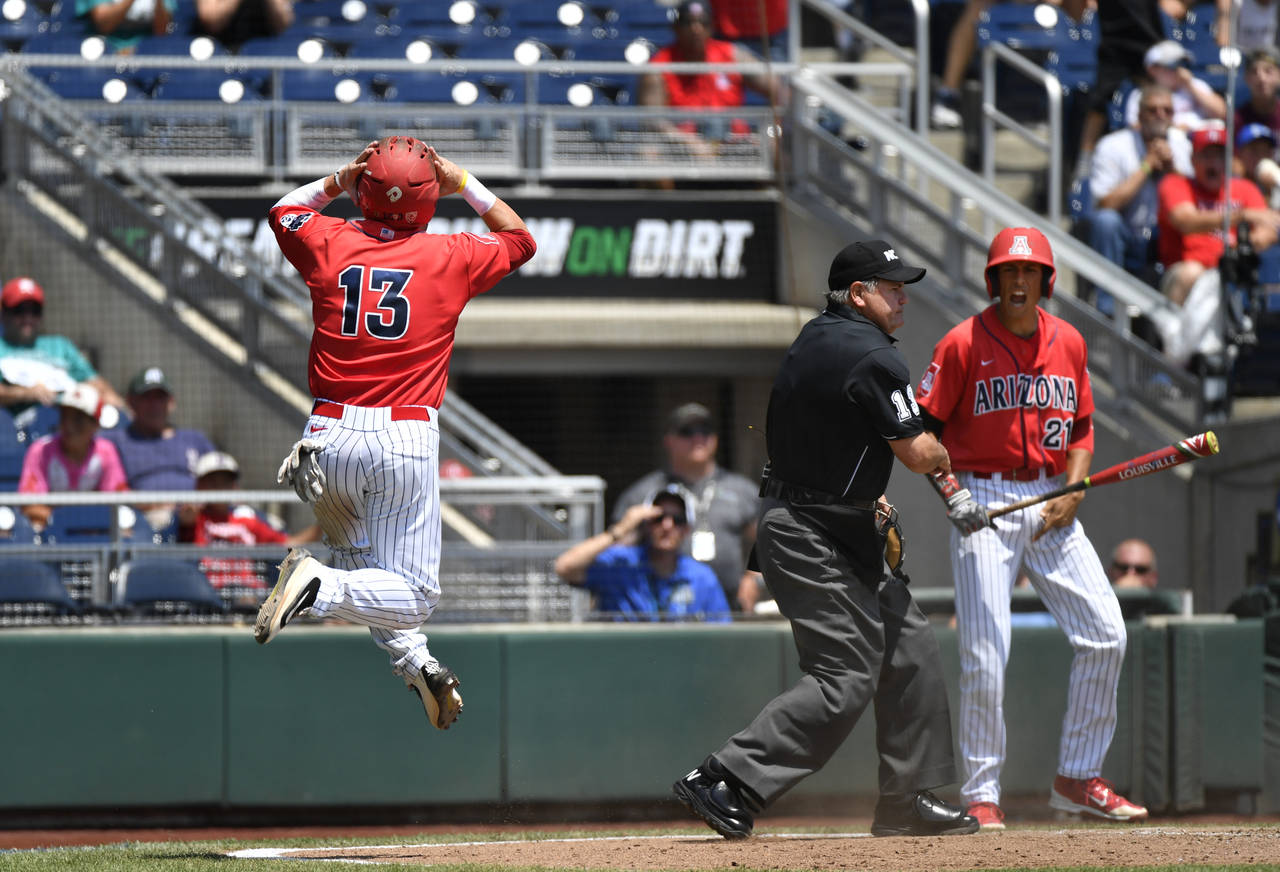 Arizona's Cody Ramer (13) reacts to being called out at home by umpire Joe Burleson against Coastal Carolina as Ryan Aguilar (21) looks on in the third inning in Game 3 of the NCAA College World Series baseball finals in Omaha, Neb., Thursday, June 30, 2016. (AP Photo/Ted Kirk)