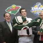 Luke Kunin, second from right, puts on his sweater as he stands with members of the Minnesota Wild management team at the NHL draft in Buffalo, N.Y., Friday June 24, 2016. (Nathan Denette/The Canadian Press via AP) MANDATORY CREDIT