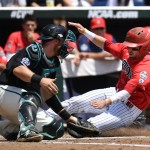 Arizona's Cody Ramer, right, is tagged out by Coastal Carolina catcher David Parrett at home in the third inning in Game 3 of the NCAA College World Series baseball finals in Omaha, Neb., Thursday, June 30, 2016. (AP Photo/Ted Kirk)