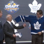 Toronto Maple Leafs general manager Lou Lamoriello, center, helps first overall pick Auston Matthews who puts on his sweater at the NHL draft in Buffalo, N.Y., Friday June 24, 2016. (Nathan Denette/The Canadian Press via AP) MANDATORY CREDIT