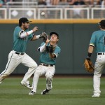 Coastal Carolina center fielder Billy Cooke, center, catches Arizona's JJ Matijevic fly ball as shortstop Michael Paez avoids a collision and Tyler Chadwick (8) looks on in the seventh inning in Game 1 of the NCAA Men's College World Series finals baseball game in Omaha, Neb., Monday, June 27, 2016. (AP Photo/Ted Kirk)
