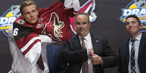 Jakob Chychrun, left, puts on his sweater as he stands with members of the Arizona Coyotes manageme...