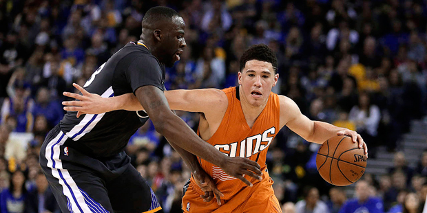 Phoenix Suns' Devin Booker, right, drives the ball against Golden State Warriors' Draymond Green du...
