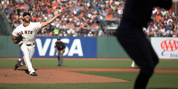 San Francisco Giants starting pitcher Madison Bumgarner, left, delivers against the Arizona Diamond...