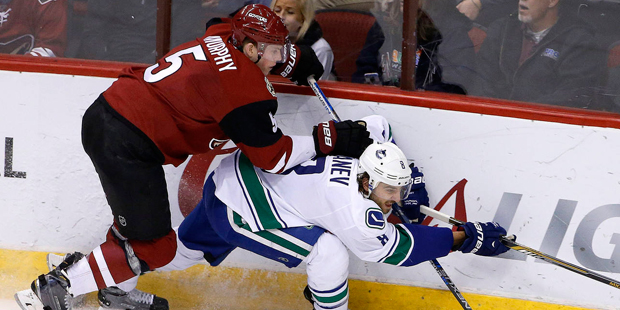 Arizona Coyotes' Connor Murphy (5) sends Vancouver Canucks' Chris Tanev, right, to the ice during t...