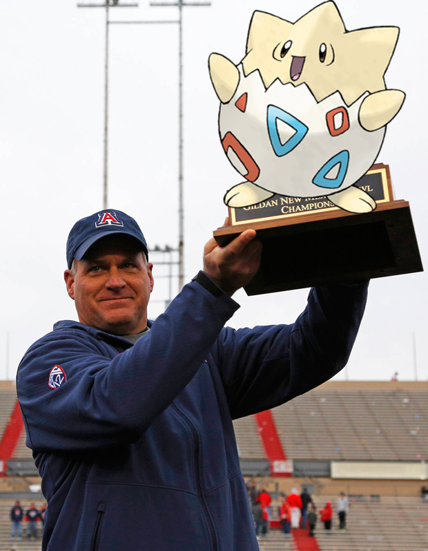 Rich Rodriguez raises the New Mexico Bowl trophy of the egg Pokemon Togepi.