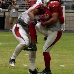 Receiver Larry Fitzgerald is hit by linebacker Kevin Minter during training camp Aug. 9. (Photo by Adam Green/Arizona Sports)