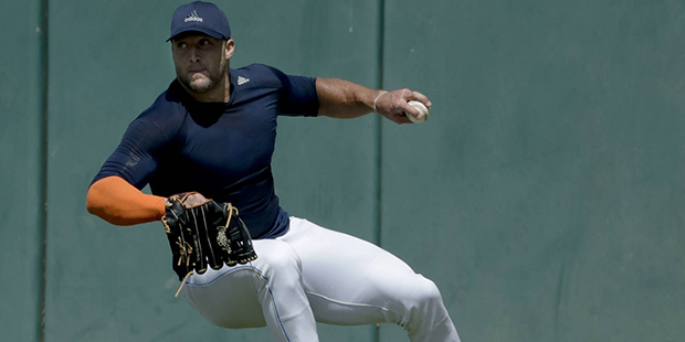 Former NFL quarterback, Tim Tebow fields a ball for baseball scouts and the media during a showcase...