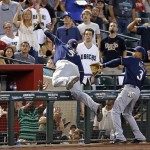 Milwaukee Brewers' Jonathan Villar, center, falls over the railing after making a leaping catch on a foul ball hit by Arizona Diamondbacks' Tuffy Gosewisch as Brewers' Orlando Arcia (3) arrives too late to help during the fourth inning of a baseball game Sunday, Aug. 7, 2016, in Phoenix. (AP Photo/Ross D. Franklin)