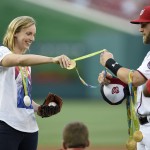Olympic gold medal swimmer Katie Ledecky, left, hands her medals to Washington Nationals' Bryce Harper, right, to hold before she threw out the ceremonial first pitch before a baseball game between the Baltimore Orioles and the Washington Nationals, Wednesday, Aug. 24, 2016, in Washington. (AP Photo/Nick Wass)