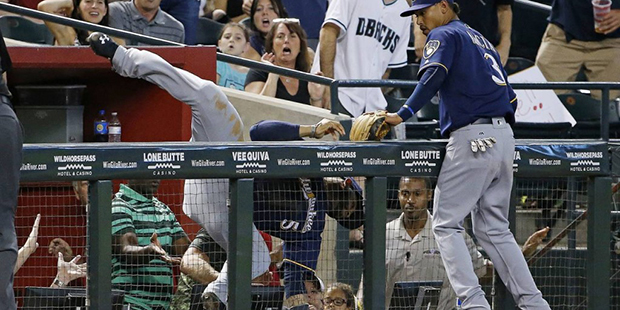 Milwaukee Brewers' Jonathan Villar (5) falls over the railing after making a leaping catch on a fou...