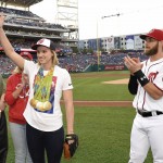 Olympic gold medal swimmer Katie Ledecky acknowledges the crowd while standing next to Washington Nationals' Bryce Harper, right, before a baseball game between the Baltimore Orioles and the Nationals, Wednesday, Aug. 24, 2016, in Washington. (AP Photo/Nick Wass)