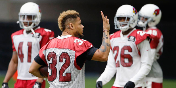 An injured Arizona Cardinals' Tyrann Mathieu (32) waves to cheering fans as he stands with teammate...