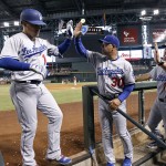 Los Angeles Dodgers' Enrique Hernandez, left, is congratulated by manager Dave Roberts (30) and teammates as he returns to the dugout following his solo home run against the Arizona Diamondbacks during the fifth inning of a baseball game, Sunday, Sept. 18, 2016, in Phoenix. (AP Photo/Ralph Freso)