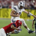 BYU quarterback Taysom Hill (7) leaps over Arizona cornerback Jace Whittaker during the first half of an NCAA college football game, Saturday, Sept. 3, 2016, in Phoenix. (AP Photo/Rick Scuteri)