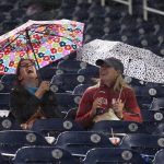 Fans sit out in the rain during a delay in the sixth inning of a baseball game between the Washington Nationals and the Arizona Diamondbacks in Washington, Wednesday, Sept. 28, 2016. (AP Photo/Manuel Balce Ceneta)