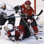 Arizona Coyotes goalie Louis Domingue makes a diving save between the legs of Los Angeles Kings' Dwight King (74) as Coyotes' Justin Hache (73) defends during the second period of a preseason NHL hockey game Monday, Sept. 26, 2016, in Glendale, Ariz. (AP Photo/Ross D. Franklin)