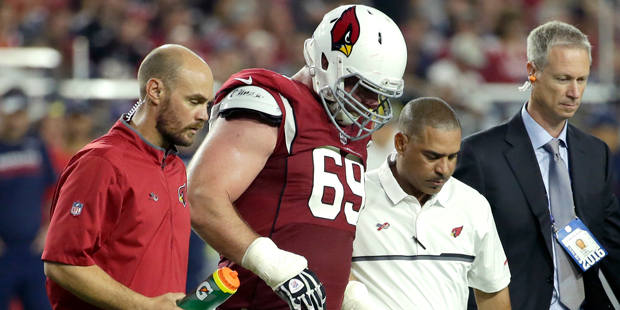 Arizona Cardinals guard Evan Mathis (69) is helped off the field after an injury against the New En...