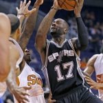 San Antonio Spurs' Jonathon Simmons (17) drives past Phoenix Suns' Eric Bledsoe, second from left, and Jared Dudley, left, for a shot during the first half of an NBA preseason basketball game, Monday, Oct. 3, 2016, in Phoenix. (AP Photo/Ross D. Franklin)