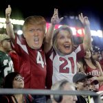 Arizona Cardinals fans with Donald Trump and Hillary Clinton masks cheer during the second half of an NFL football game against the New York Jets, Monday, Oct. 17, 2016, in Glendale, Ariz. The Cardinals won 28-3. (AP Photo/Rick Scuteri)