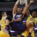 Phoenix Suns center Alex Len, center, hangs from the rim after a dunk, between Los Angeles Lakers forwards Thomas Robinson, right, and Larry Nance Jr. during the second half of an NBA preseason basketball game in Anaheim, Calif., Friday, Oct. 21, 2016. (AP Photo/Kelvin Kuo)