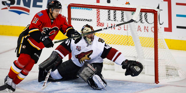 Arizona Coyotes goalie Mike Smith, right, protects the net as Calgary Flames' Mikael Backlund, chas...