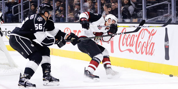 Arizona Coyotes' Laurent Dauphin, right, is defended by Los Angeles Kings' Kurtis MacDermid during ...