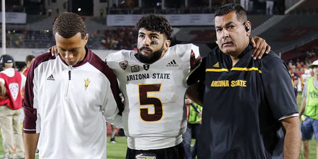 Arizona State quarterback Manny Wilkins (5), center, is helped off the field after being injured du...