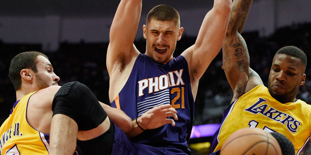 Phoenix Suns center Alex Len, center, hangs from the rim after a dunk, between Los Angeles Lakers f...