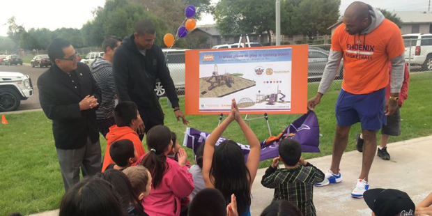 Earl Watson and P.J. Tucker  help reveal a playground design in Guadalupe, Ariz....