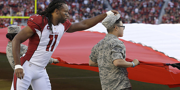 Arizona Cardinals wide receiver Larry Fitzgerald (11) adjusts the hat of one of the people holding ...
