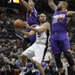 San Antonio Spurs guard Tony Parker (9) drives between Phoenix Suns defenders P.J. Tucker (17) and Phoenix Suns forward Marquese Chriss (0) during the first half of an NBA basketball game, Wednesday, Dec. 28, 2016, in San Antonio. (AP Photo/Eric Gay)