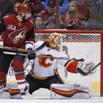 Calgary Flames goalie Chad Johnson, right, pushes the puck wide on a shot as Arizona Coyotes center Martin Hanzal (11) looks on during the first period of an NHL hockey game Thursday, Dec. 8, 2016, in Glendale, Ariz. (AP Photo/Ross D. Franklin)