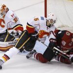 Calgary Flames defenseman Mark Giordano (5) sends Arizona Coyotes right wing Tobias Rieder (8) to the ice after Flames' goalie Chad Johnson (31) makes a save during the third period of an NHL hockey game Thursday, Dec. 8, 2016, in Glendale, Ariz. The Flames defeated the Coyotes 2-1 in overtime. (AP Photo/Ross D. Franklin)