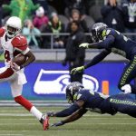 Arizona Cardinals' J.J. Nelson (14) looks back as Seattle Seahawks' Steven Terrell, center, and Jeremy Lane tumble behind as he runs for a touchdown after a pass reception in the first half of an NFL football game, Saturday, Dec. 24, 2016, in Seattle. (AP Photo/Ted S. Warren)