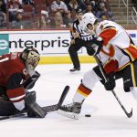 Arizona Coyotes goalie Mike Smith, left, makes a save on a shot by Calgary Flames right wing Alex Chiasson, right, during the first period of an NHL hockey game Thursday, Dec. 8, 2016, in Glendale, Ariz. (AP Photo/Ross D. Franklin)