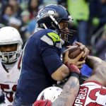 Seattle Seahawks quarterback Russell Wilson, center, is held back by Arizona Cardinals defensive end Calais Campbell (93) while retaining the ball on a touchdown-attempt in the first half of an NFL football game, Saturday, Dec. 24, 2016, in Seattle. (AP Photo/Ted S. Warren)