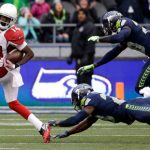 Arizona Cardinals' J.J. Nelson (14) looks back as Seattle Seahawks' Steven Terrell, center, and Jeremy Lane tumble behind as he runs for a touchdown after a pass reception in the first half of an NFL football game, Saturday, Dec. 24, 2016, in Seattle. (AP Photo/Ted S. Warren)
