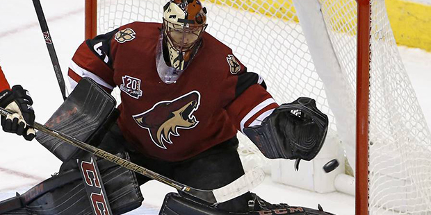 Arizona Coyotes goalie Mike Smith, right, makes a save on a redirect from Calgary Flames left wing ...