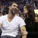 Olympic swimmer Michael Phelps and his wife Nicole shares a light moment during an NBA basketball game between the Cleveland Cavaliers and the Phoenix Suns in Phoenix, Ariz., Sunday, Jan. 8, 2017. (Patrick Breen/The Arizona Republic via AP)