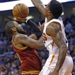 Cleveland Cavaliers guard Kyrie Irving, left, gets off a shot over Phoenix Suns guard Eric Bledsoe, right, during the first half of an NBA basketball game Sunday, Jan. 8, 2017, in Phoenix. (AP Photo/Ross D. Franklin)