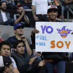 A Phoenix fan holds up a sign that reads in Spanish "I am Phoenix" prior a regular-season NBA basketball game against San Antonio, in Mexico City, Saturday, Jan. 14, 2017. (AP Photo/Rebecca Blackwell)